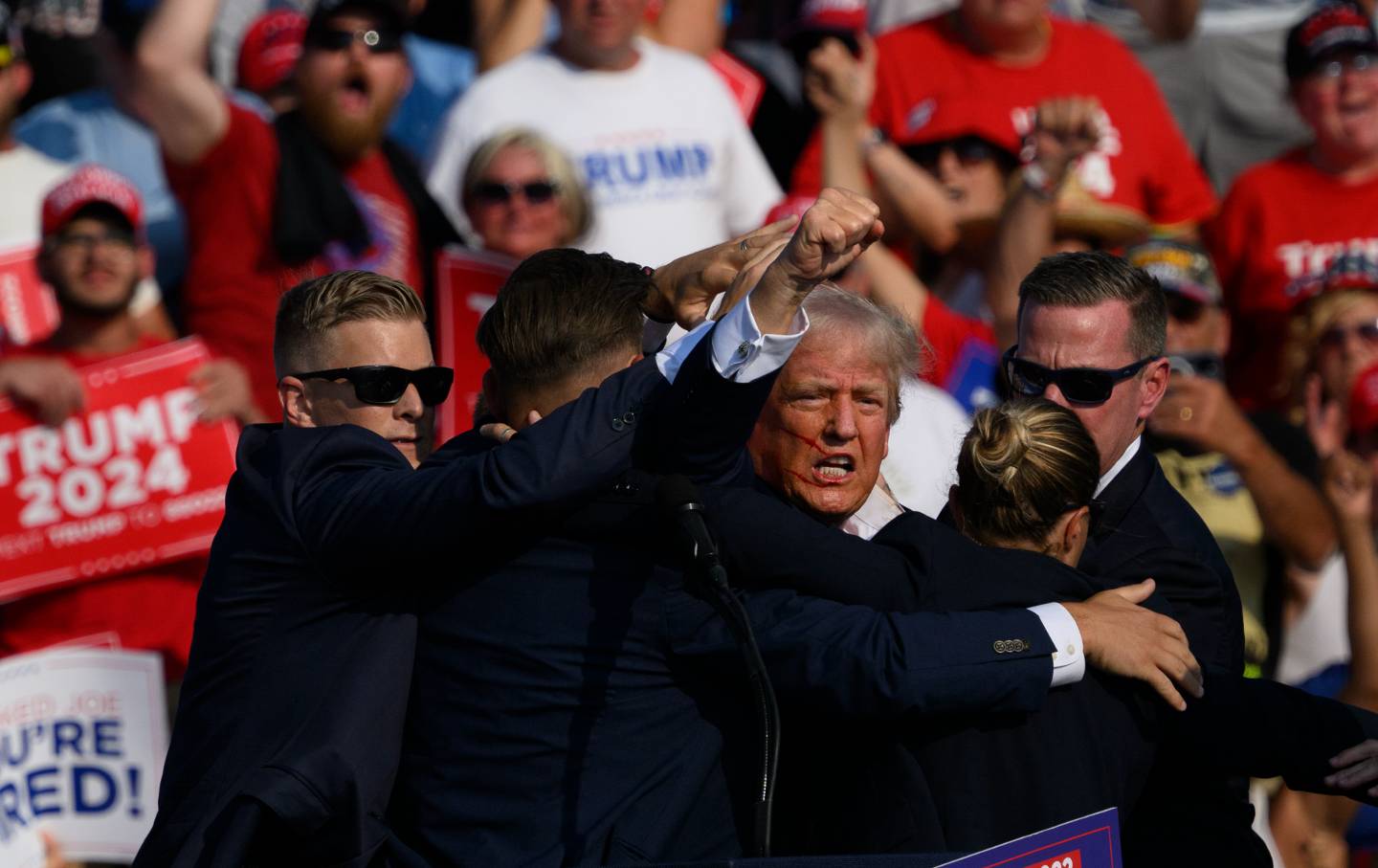 Republican presidential candidate, former president Donald Trump is whisked away by Secret Service after shots rang out at a campaign rally at Butler Farm Show Inc. on July 13, 2024, in Butler, Pennsylvania.